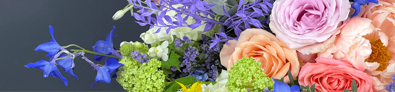orange and pink roses with peonies and foliage in bright blue, yellow and purple vibrant colours blooms.